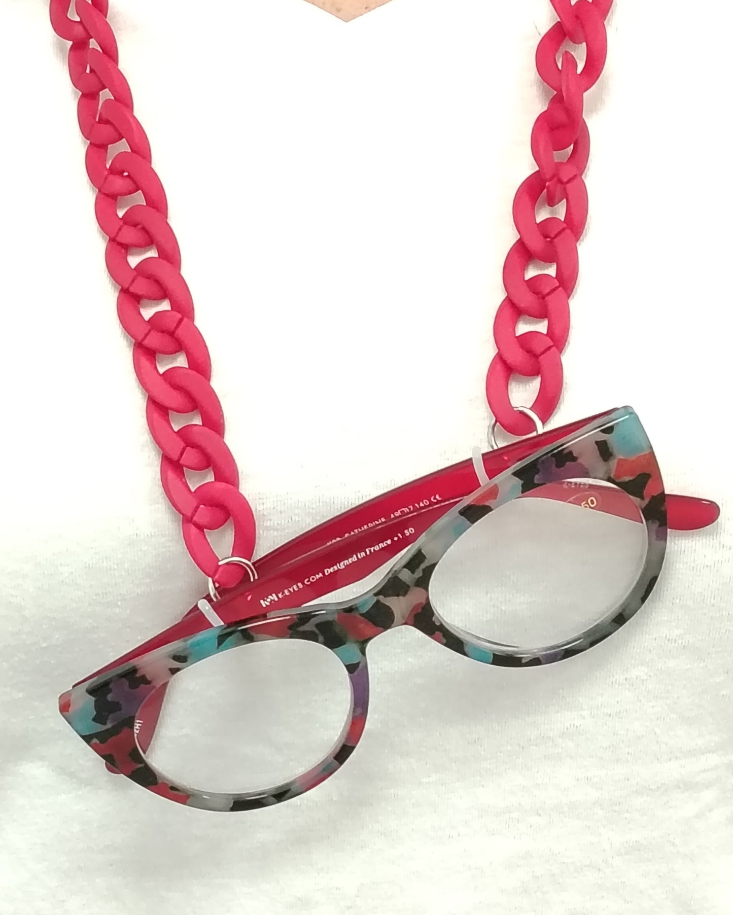 gafas premontadas para presbicia modelo k eyes k38-catherine con montura cat-eyes en acetato estampado multicolor, acompañadas de una cadena cuelga gafas de eslabones gruesos en rojo mate