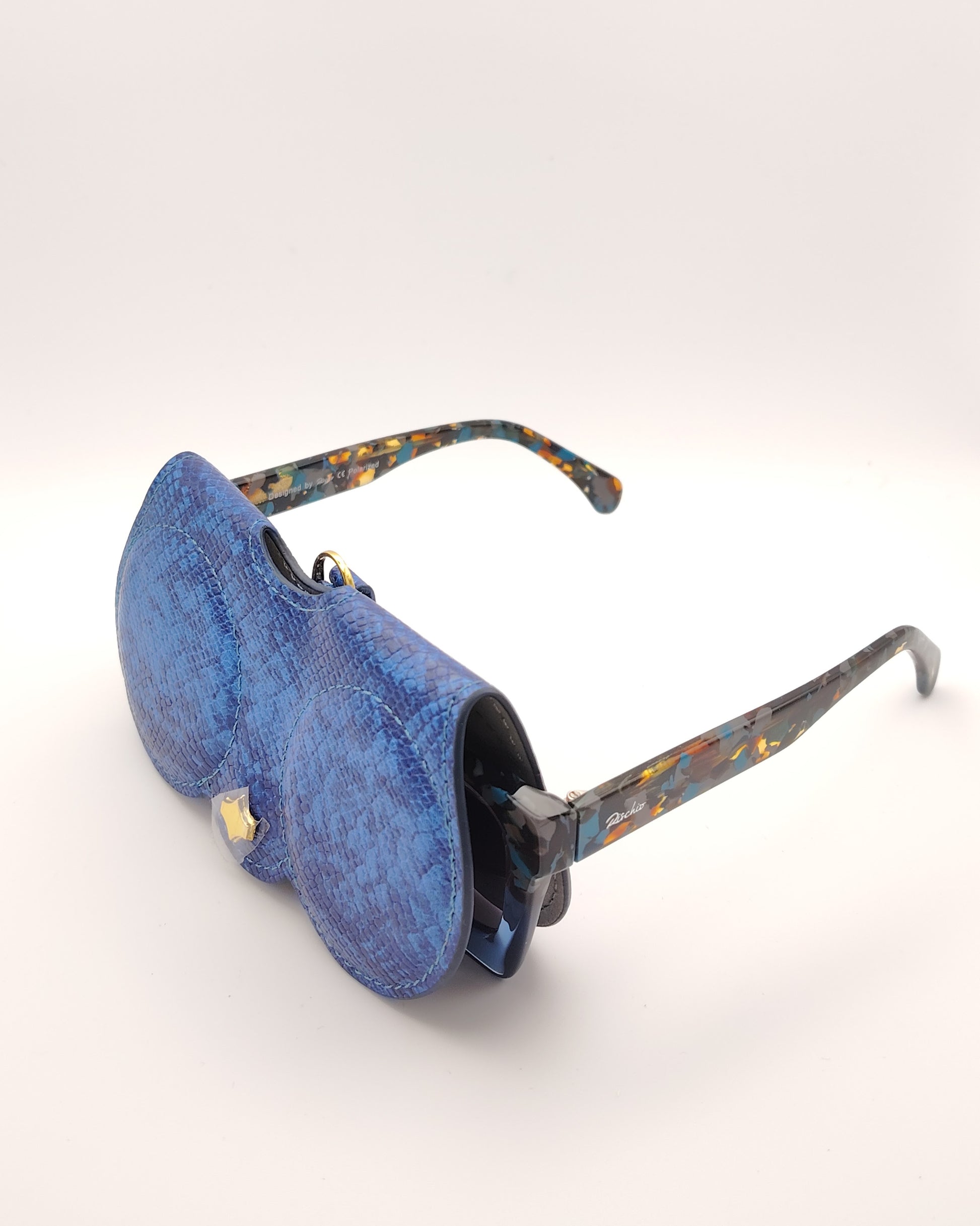 estuche cover chic en acabado efecto piel de serpiente azul, con asa desmontable y detalle dorado, ideal para colgar del bolso