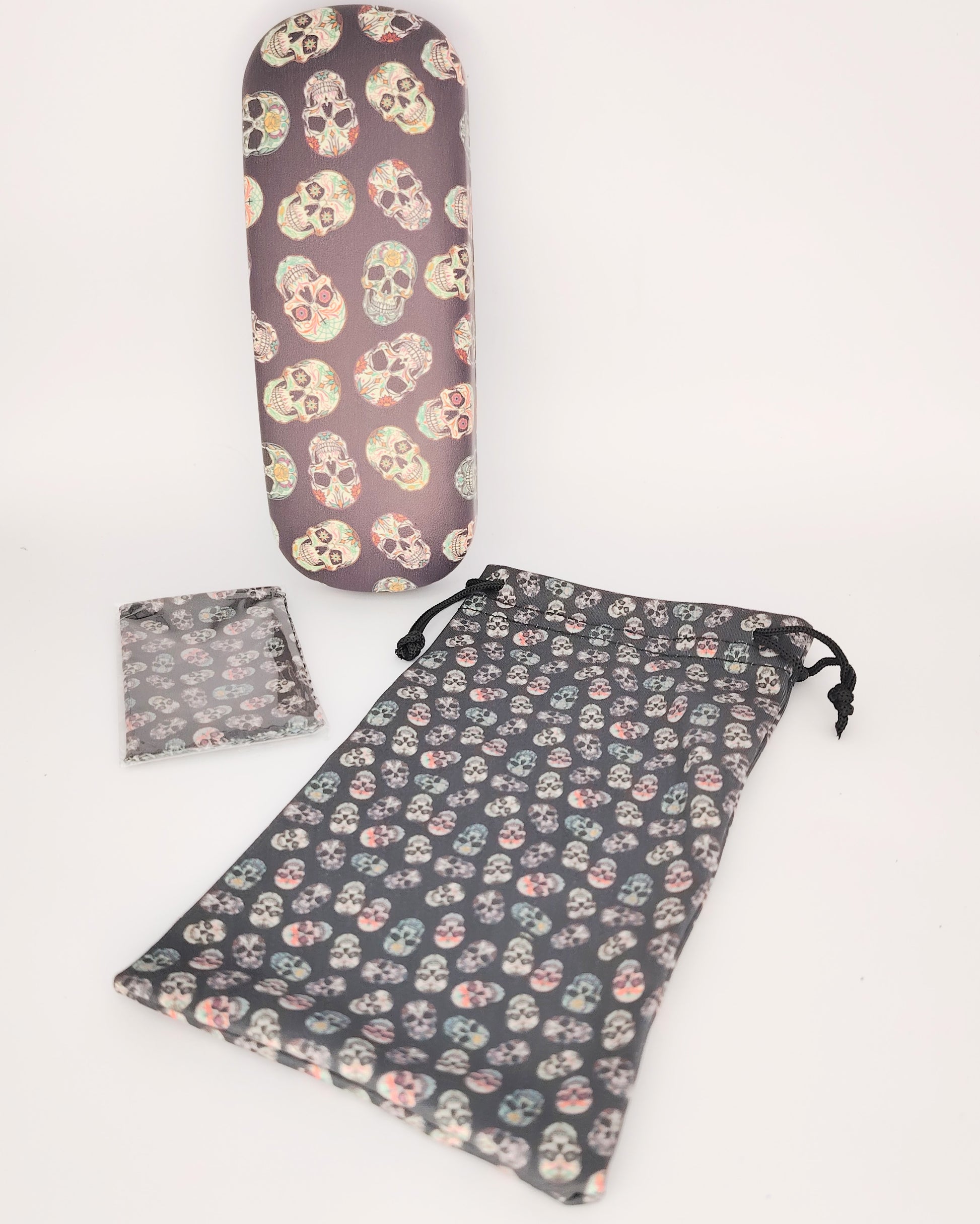 pack para gafas formado por estuche rígido, funda de tela blanda y gamuza limpia gafas, todo ello color negro de fondo en estampado de calaveras multicolor