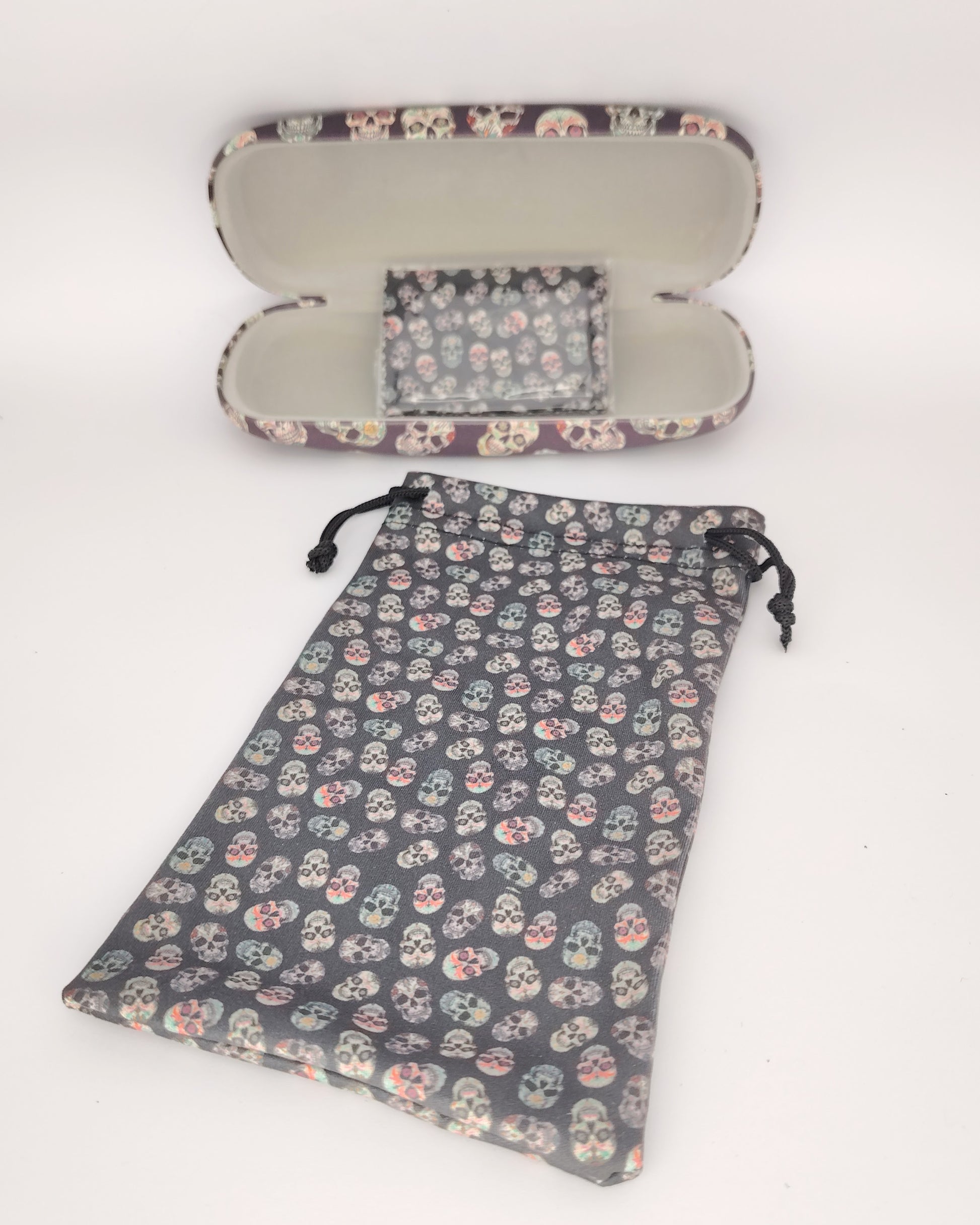 pack para gafas formado por estuche rígido, funda de tela blanda y gamuza limpia gafas, todo ello color negro de fondo en estampado de calaveras multicolor