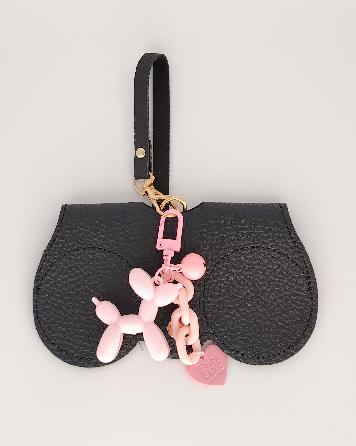 estuche para gafas especialmente diseñado para colgar del bolso cover en  color negro con textura elegante acompañado de un llavero perro globo rosa