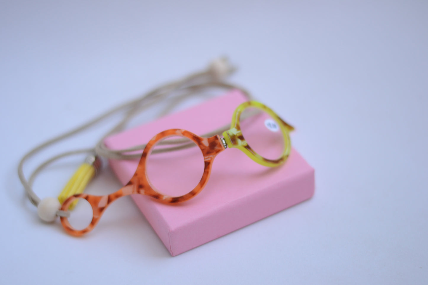 colgante lupa impertilente en tonos naranja y amarillo con correa de cuero abalorios decorativos y borla a juego para llevar siempre a mano con un toque elegante y funcional