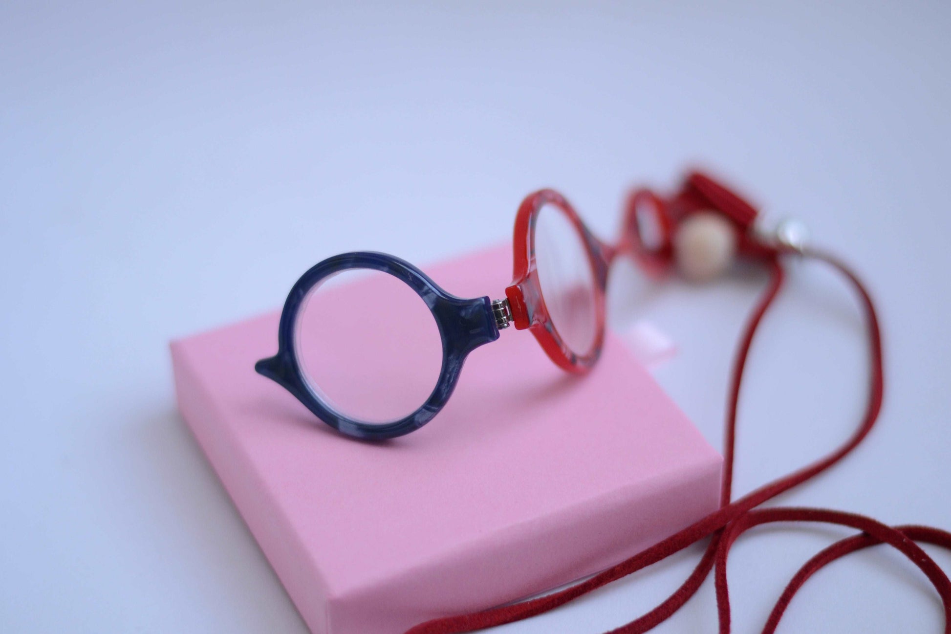 colgante lupa impertilente en combinación de colores rojo y azul con correa de cuero abalorios decorativos y borla roja diseñado para aportar funcionalidad con un toque de estilo