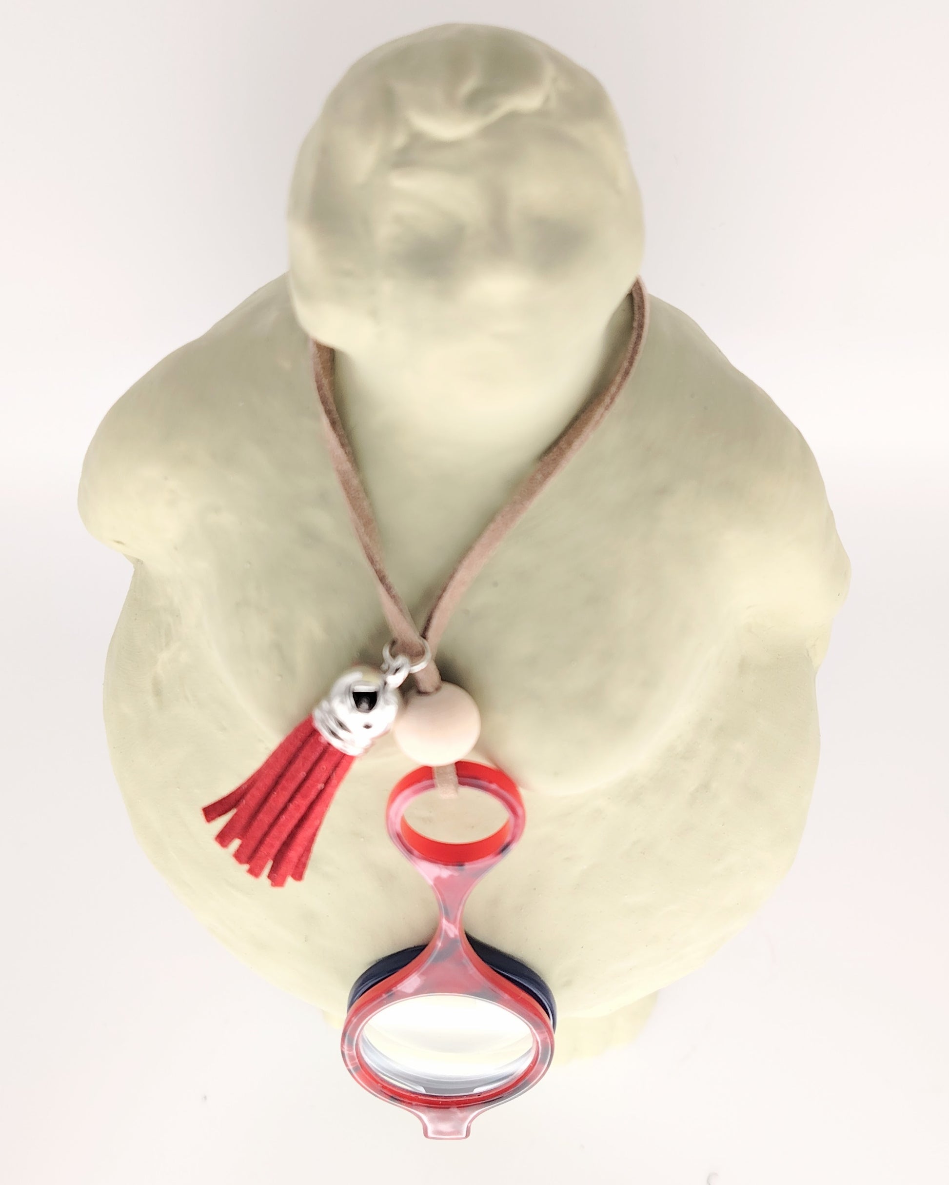 colgante lupa impertilente en rojo y azul con correa de cuero beige, detalle de borla roja y abalorios plateados, un accesorio práctico y sofisticado